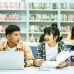 Women read books and men use laptops to search for books in libraries.